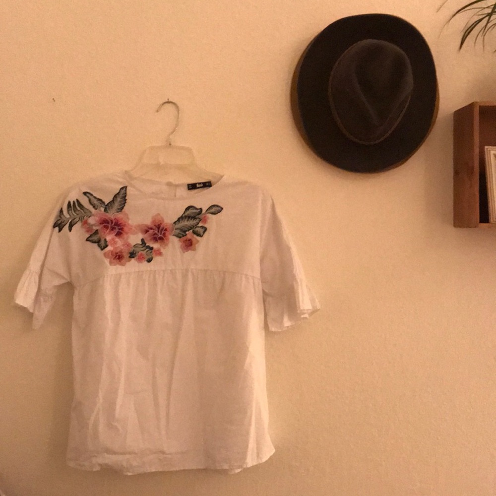 Cute blouse with embroidered flower across neck